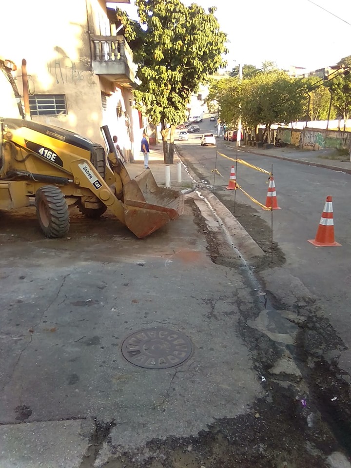 À esquerda, um trator na calçada. À direita, cones dispostos na rua isolando a obra finalizada da sarjeta.